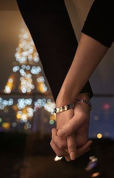 two people holding hands in front of the eiffel tower at night, paris