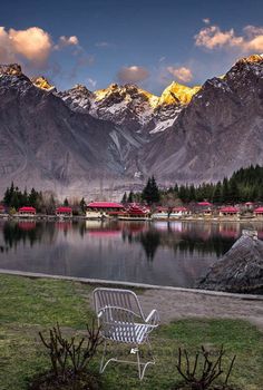 a bench sitting on top of a grass covered field next to a lake and mountains