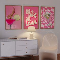 two pink posters on the wall above a white dresser