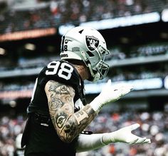 a football player with tattoos on his arm and arms is in the air as he walks off the field