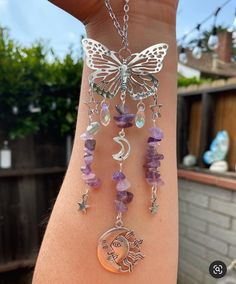 a woman's arm with a butterfly, moon and star charm bracelet on it