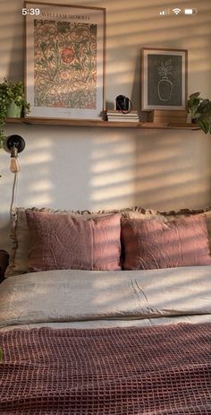 a bed with pillows, blankets and pictures on the wall above it in a bedroom