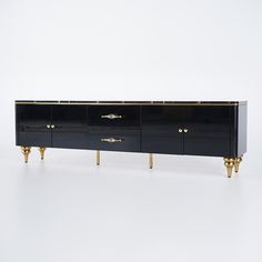 a black and gold sideboard with three brass legs on white background in an empty room