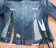 a pair of scissors are laying next to a jean jacket that has holes cut into it