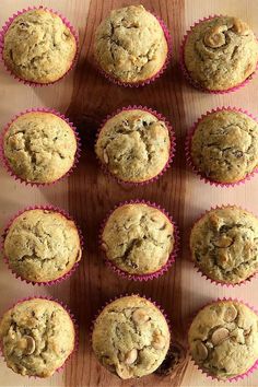 twelve muffins on a wooden board with pink paper liner