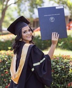 a woman in graduation gown holding up her diploma