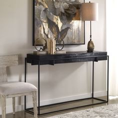 a black console table with two lamps and a painting on the wall in front of it