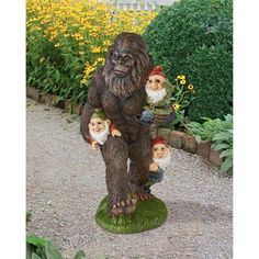 a statue of a bigfoot with three gnomes on it's back in the garden