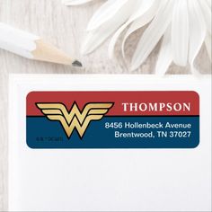 a business card with a wonder woman logo on it and a pencil next to it