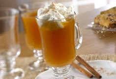 two glasses filled with drinks sitting on top of a table next to cookies and muffins