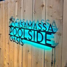 a wooden fence with a neon sign that reads, gasmassa poolside oasis