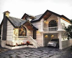 a car is parked in front of a house with a porch and stairs on the second floor