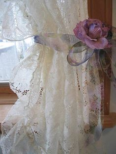 a white curtain with lace and flowers on it