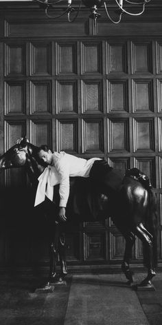 a black and white photo of a man standing next to a horse