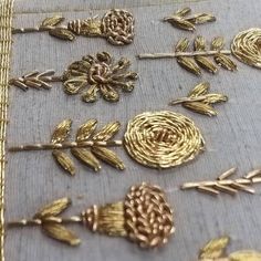 many different types of gold brooches on a piece of cloth with some pine cones