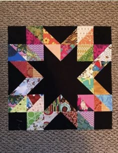 a black square with colorful patchwork on the top and bottom, surrounded by smaller squares