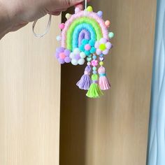 a hand holding a rainbow decoration hanging from a door