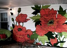 a painting on the side of a house with red flowers and green leaves painted on it