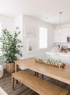 a wooden table sitting in the middle of a kitchen next to a potted plant