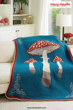 a crocheted blanket with mushrooms on it in the middle of a living room