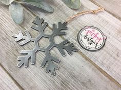 a snowflake ornament sitting on top of a wooden table next to a plant