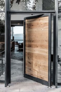 an open wooden door on the outside of a building with glass walls and doors leading to a balcony