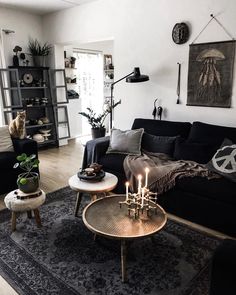 a living room filled with black furniture and lots of pillows on top of a rug