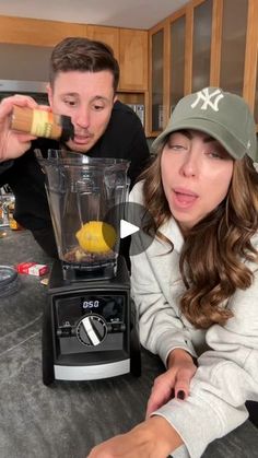 a man and woman are making something in a blender with lemons on it