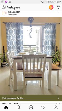 a white table and chairs in front of a window with curtains on the windowsill