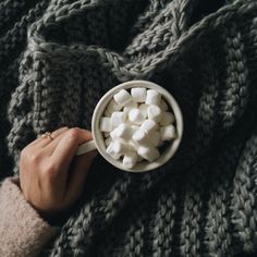 a person holding a mug filled with marshmallows