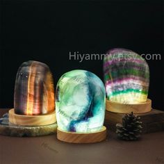 three different colored glass vases sitting on top of a table next to a pine cone