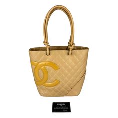 This Classic Chanel Cambon Ligne Tote Is Crafted From Quilted Beige Calfskin Leather. Finished With Double Leather Top Handles, This Timeless Piece Will Look Chic Wherever You Go. With Ample Interior Space, This Tote Is Functional For Everyday Wear. Elevate Your Look With This Refined And Luxurious Tote From Chanel. Pre-Owned Condition: Good, Signs Of Wear (See Images) Beige Quilted Calfskin Leather Large Cc Logo Motif Silver-Tone Hardware Zipper Closure Yellow Cc Printed Fabric Interior Lining Chanel Cambon, Chanel Tote Bag, Classic Chanel, Chanel Tote, Shopping Chanel, Cc Logo, Branded Handbags, Printed Fabric, Chanel Handbags