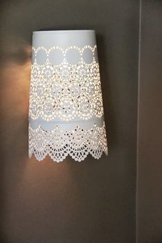 a lamp that is on the wall next to a light fixture with a lace shade