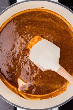 the sauce is being stirred with a wooden spatula in a pan on the stove