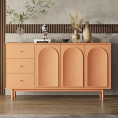 an orange sideboard with vases and plants on it in front of a wall