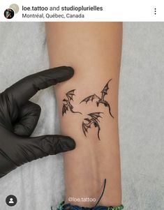 a woman's arm with tattoos on it and two small bats flying above her