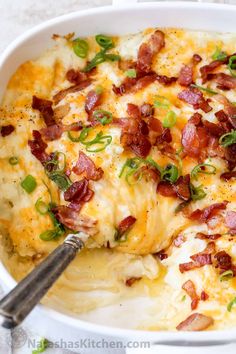 loaded mashed potato casserole with bacon and green onions in a white dish