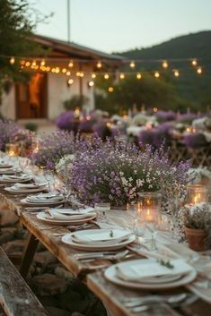 a long table set up with plates and place settings for an outdoor dinner or party