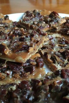 a white plate topped with lots of chocolate and nuts covered desserts on top of a wooden table