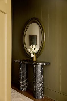 a mirror sitting on top of a table next to a vase with flowers in it