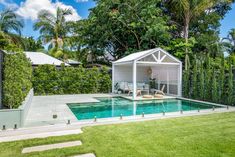 a backyard with a pool, deck and gazebo surrounded by trees in the background