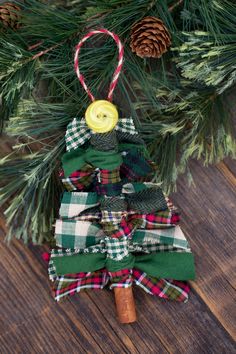 a christmas tree ornament hanging from a pine tree with a button on it