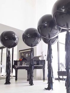 large black balloons are in the middle of an open room with piano and other furniture