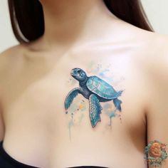 a woman's chest with a watercolor tattoo design on the top of it