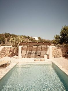 an outdoor swimming pool in the middle of a desert area with lounge chairs around it