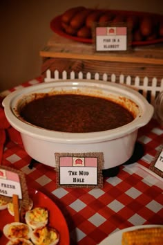 a red and white checkered table cloth with food on it, including an oval casserole dish