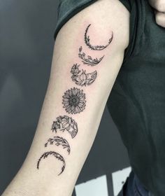 a woman's arm with flowers and crescents on it, in black ink