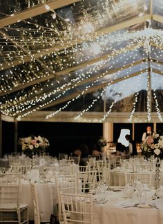 the inside of a tent with tables and chairs set up for a wedding reception at night