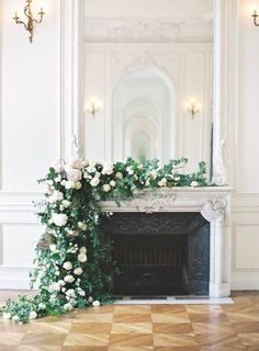 a fireplace decorated with white flowers and greenery