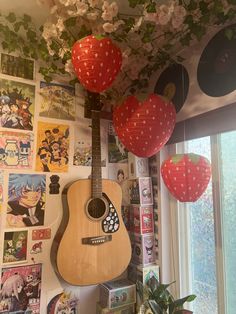 a guitar hanging from the ceiling in front of a wall with pictures and balloons on it